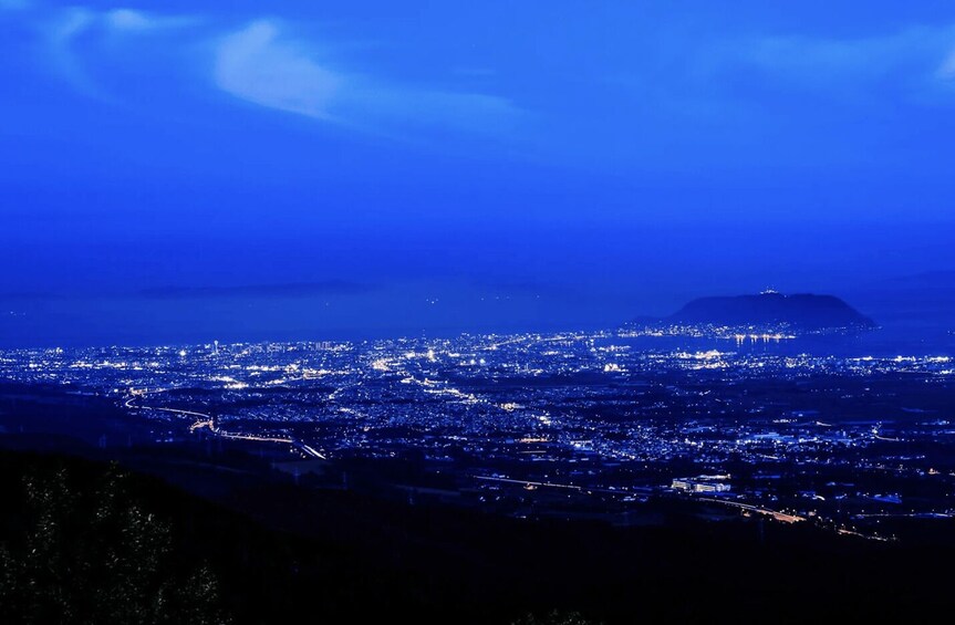 A cityscape at night with a prominent mountain in the background. 1