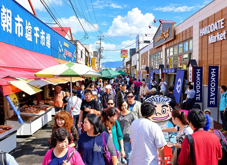 A busy street market with people walking and vendors selling goods. 5