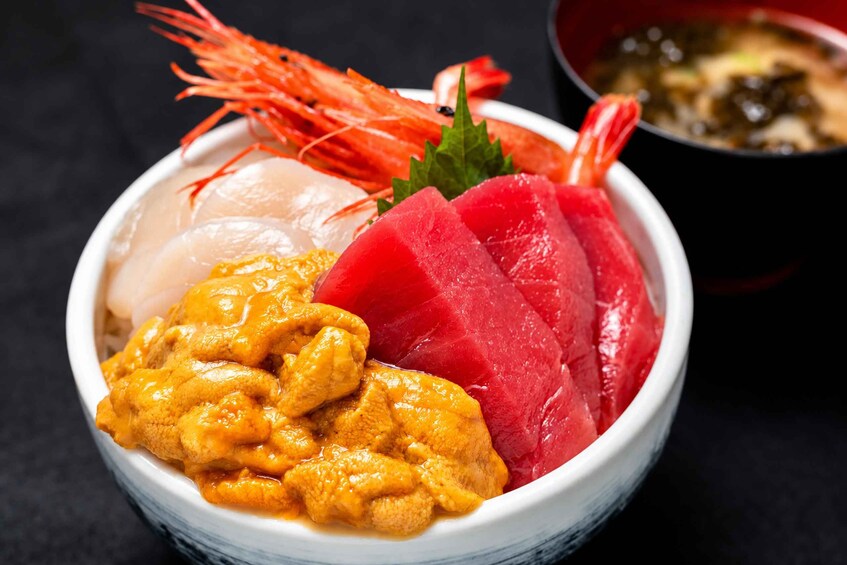 A bowl of sashimi with shrimp, fish, and chicken. 4