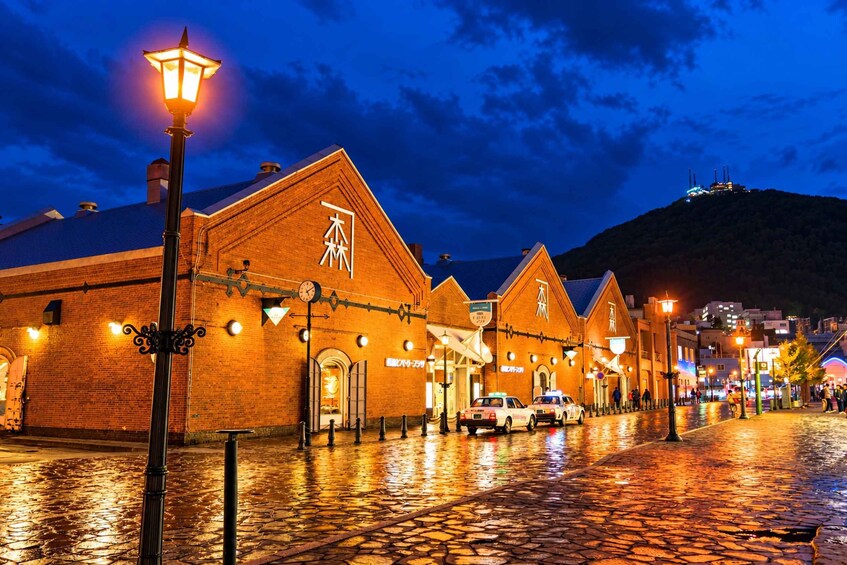 A brick building with illuminated signage and a cobblestone street at night. 3