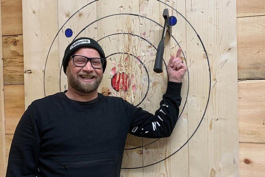 A person holding a hammer, standing in front of a wooden board with circular targets. 5
