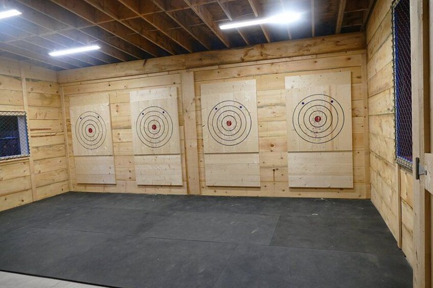 An indoor archery range with four wooden target boards. 3