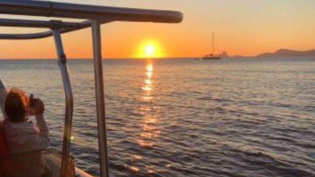A sunset over the ocean with a boat and a sailboat in the distance. 3