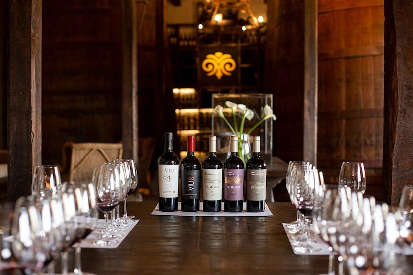 A wine tasting setup with bottles and glasses on a wooden table. 1