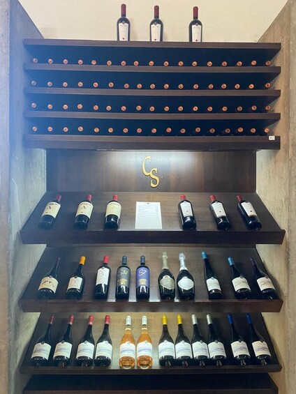 A wine rack with multiple shelves holding wine bottles. 4