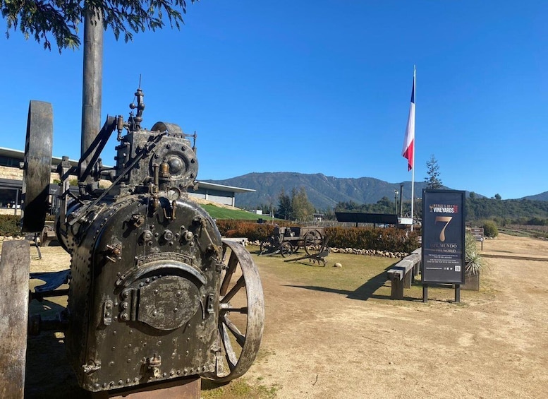 A vintage tractor with a large wheel, a flag, and a sign indicating 'World's Best Vineyards 7'. 4