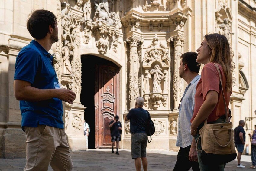 A group of people standing in front of a historic building with ornate carvings and a large wooden door. 4