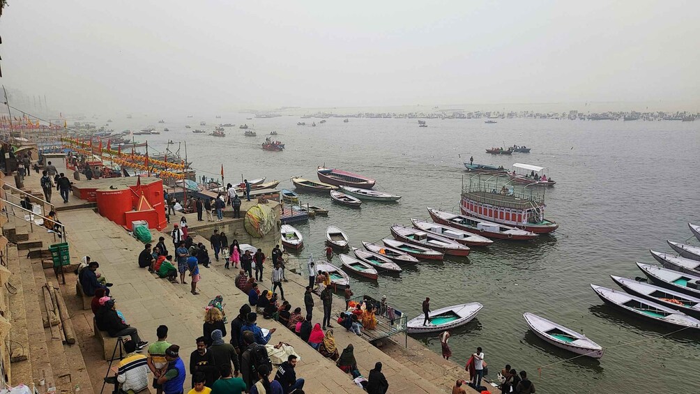 A busy riverside with numerous boats docked and people walking along the steps. 3