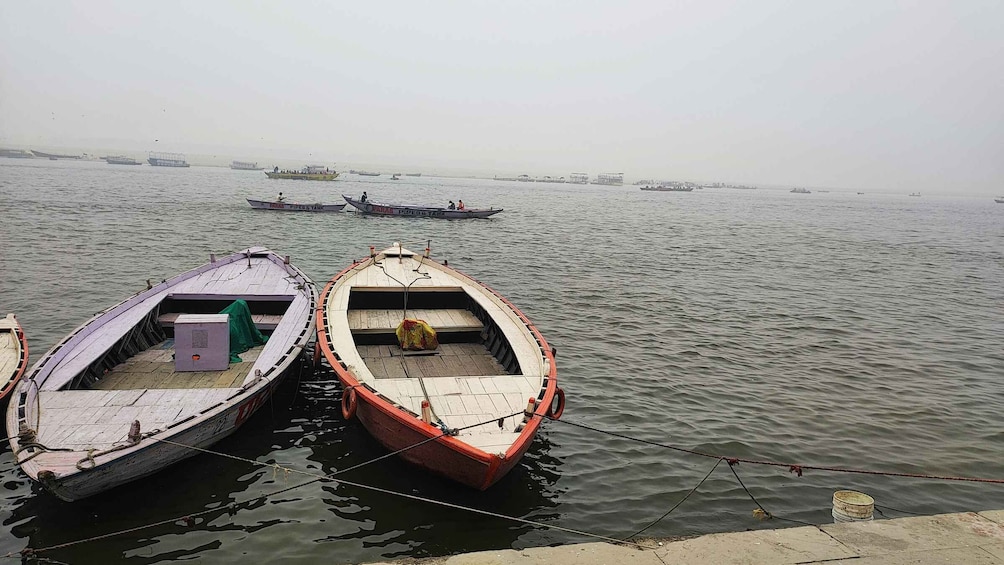 Two boats tied to a dock, with a calm river and distant boats in the background. 4