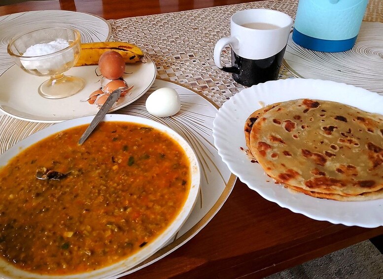 A meal with a bowl of soup, a plate of flatbread, a banana, a cup of coffee, and a glass of milk. 3