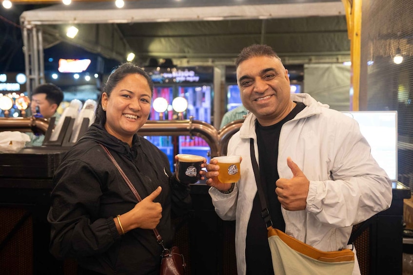 Two people holding mugs with 'SUNRISE' written on them, standing in a food court with a counter and other people in the background. 4