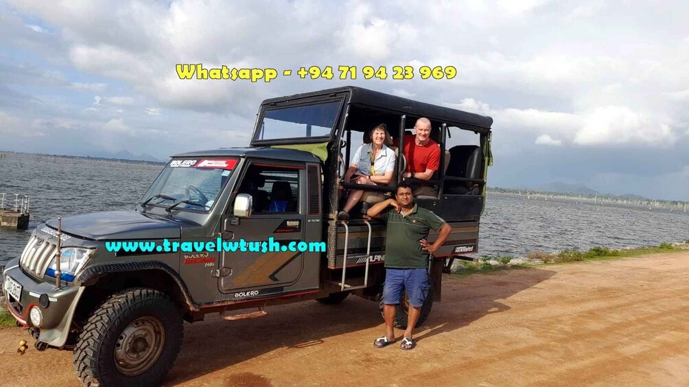 A Bolero vehicle parked by a lakeside with three people inside. 3