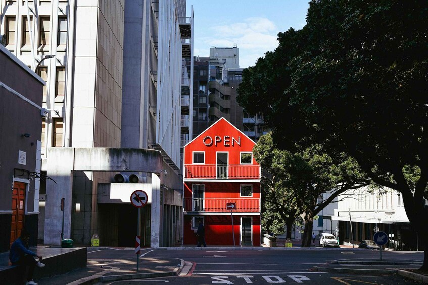 A red building with an 'OPEN' sign, a 'STOP' sign, and a blue directional sign on a city street. 2