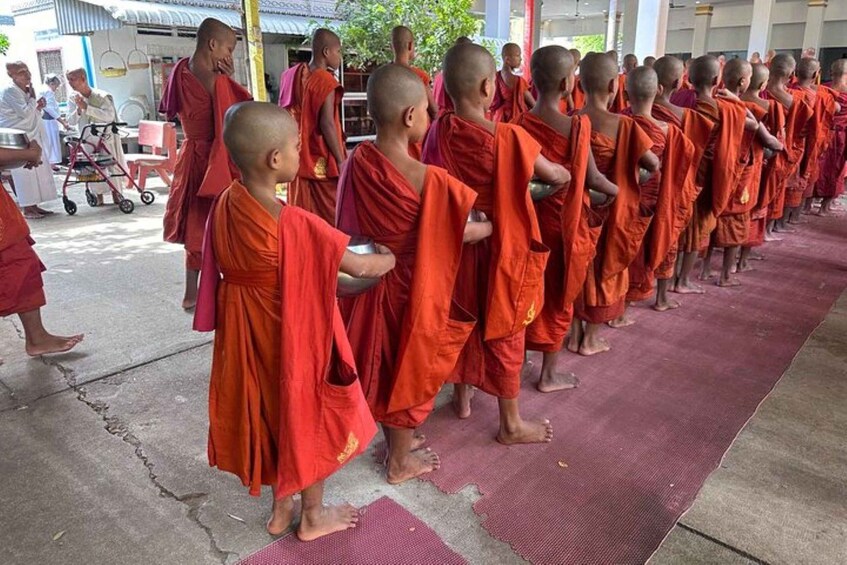 Monks in orange robes lined up on a mat. 3