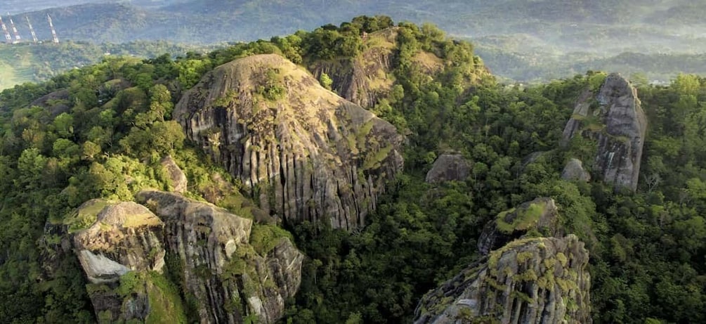 A mountainous landscape with prominent rock formations and dense forest. 3