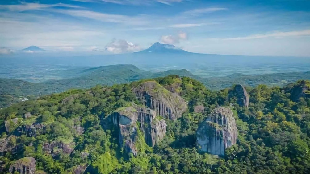 A mountainous landscape with prominent rock formations and dense green vegetation. 2