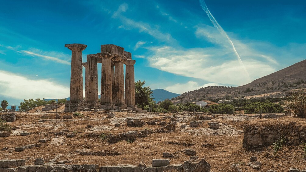 Ancient ruins with columns, a dry landscape, and a mountain in the background. 1