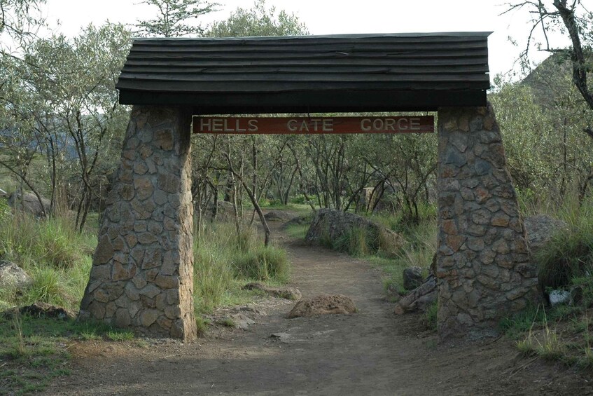 A stone archway with the inscription "HELLS GATE CORGE" in a natural setting with trees and a dirt path. 4