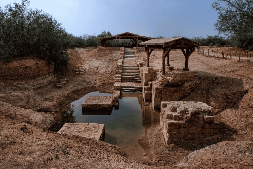 A historical site with a water channel, stone steps, and wooden structures. 2