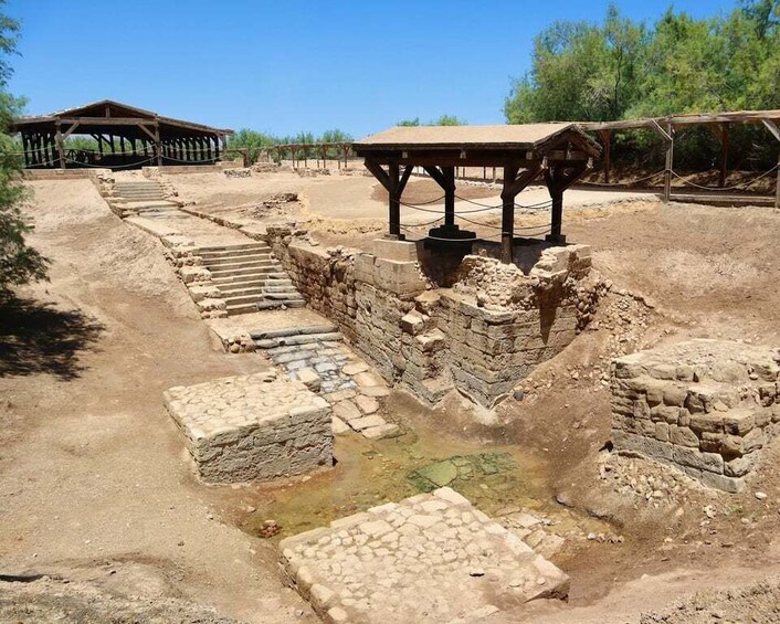 An archaeological site with stone structures and a wooden shelter. 3