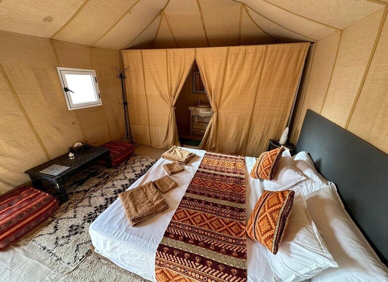 A tent with a bed, a small table, and a window. 3
