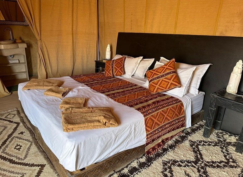 A bed with patterned bedding, a headboard, and a bedside table with a candle. 4