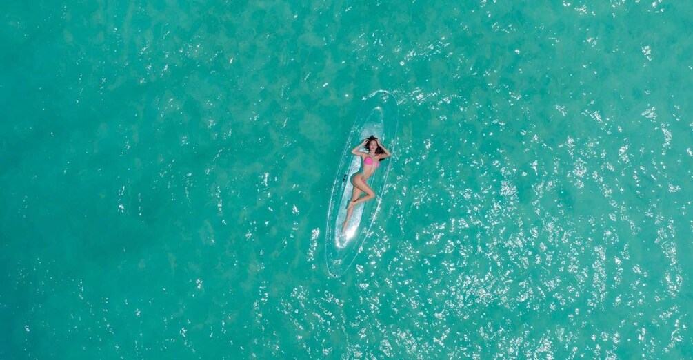 Una persona tendida sobre una tabla de surf en aguas turquesas. 4