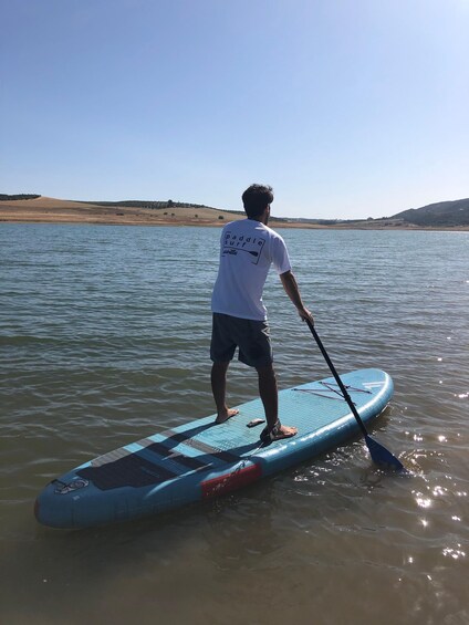 A person paddleboarding on a calm lake with distant hills. 2