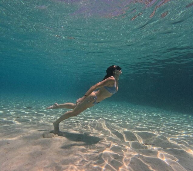 A person swimming underwater in clear water. 1