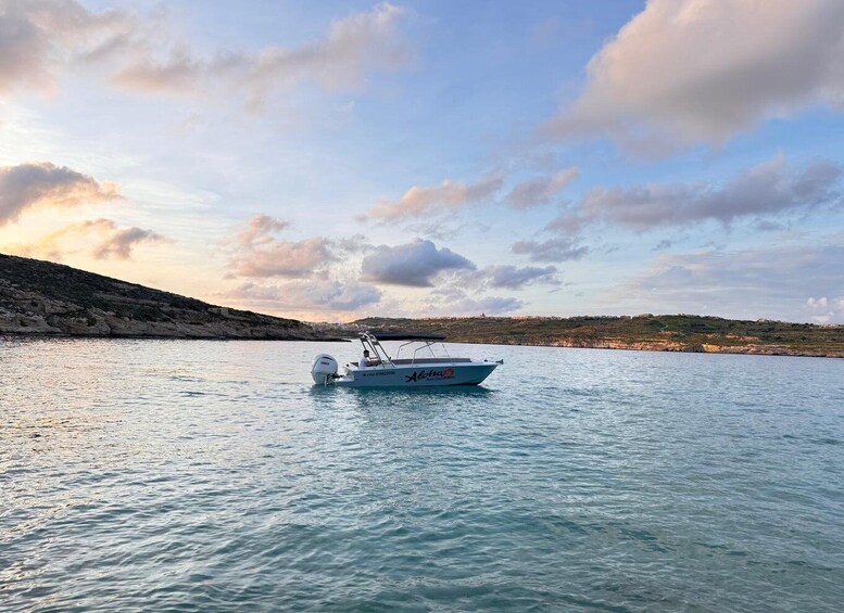A small boat on calm water with a rocky shoreline and a cloudy sky. 5