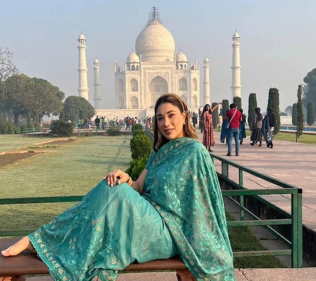 A person sitting on a bench with the Taj Mahal in the background. 2