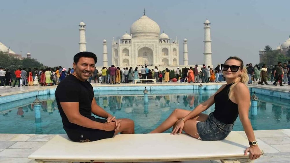 A couple sitting by a pool with the Taj Mahal in the background. 4