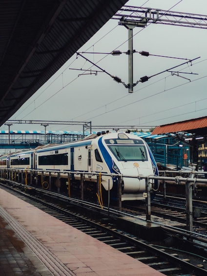 A train at a station with overhead electrical lines and a covered platform. 2