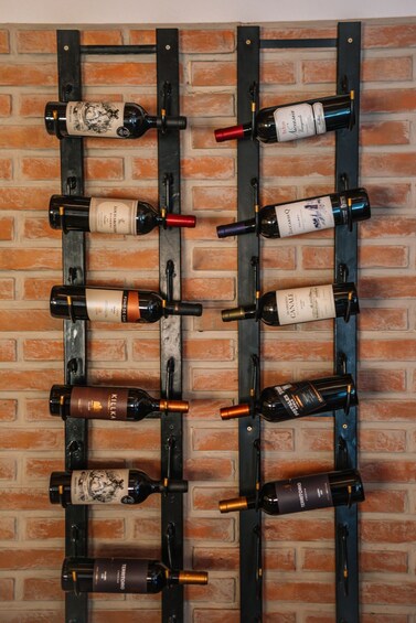 A wine rack with bottles against a brick wall. 2