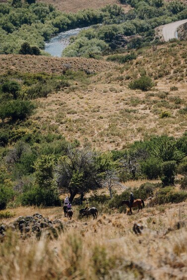 A river winding through a dry, hilly landscape with sparse vegetation and a dirt road curving through the terrain. 4