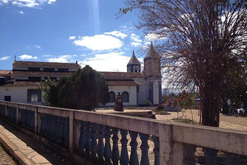 A bridge with a railing, a church with a bell tower, and a tree. 4