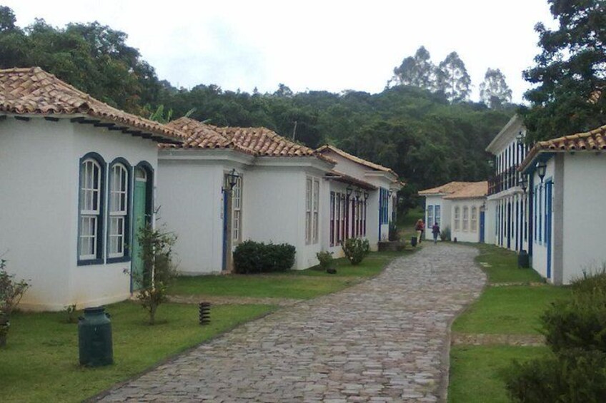 A cobblestone path leading through a row of white buildings with blue trim and tiled roofs. 3