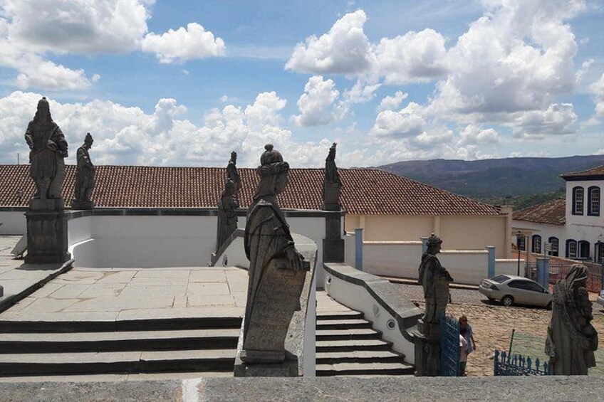 A rooftop with statues, a staircase, and buildings in the background. 5