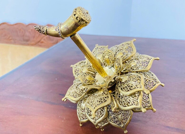 A brass hammer with intricate designs on a wooden surface. 4