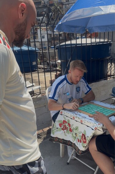 A person playing a board game at an outdoor table with a floral tablecloth. 2