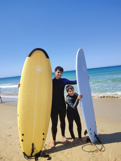 Three people holding surfboards on a beach. 5