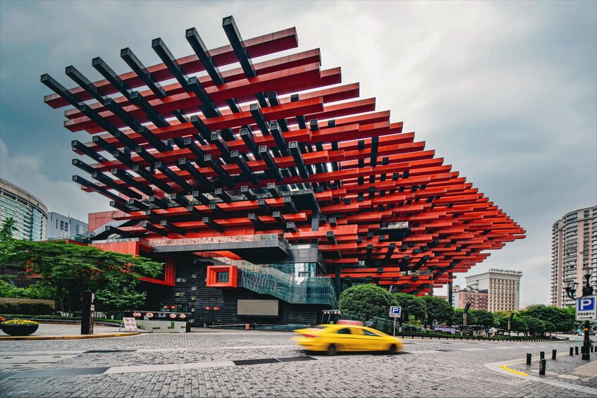 A modern building with a unique red and black facade, surrounded by urban infrastructure. 2