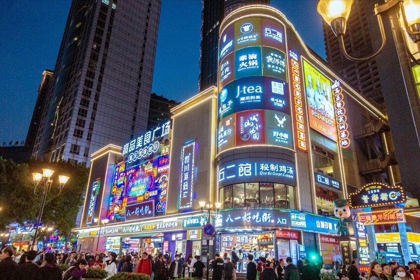 A busy urban street at night with illuminated signs and buildings. 4