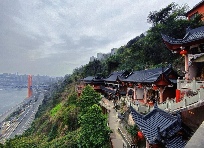 A traditional Chinese architectural structure with red lanterns, a river, and a modern bridge in the background. 5