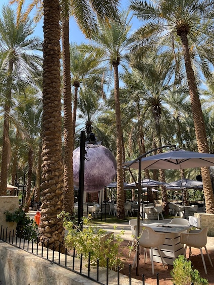 A tropical outdoor dining area with palm trees, tables, and umbrellas. 5