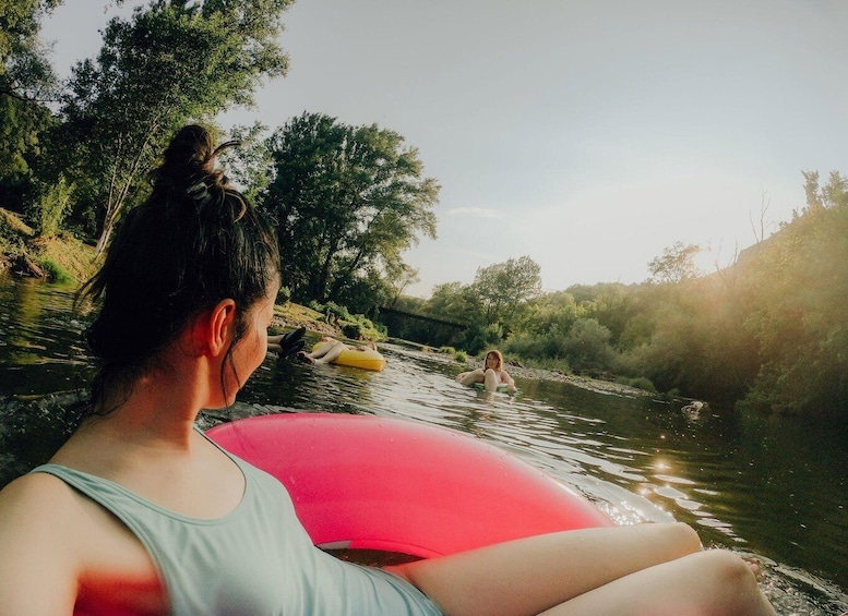 A person on a red inflatable tube in a river surrounded by trees. 5