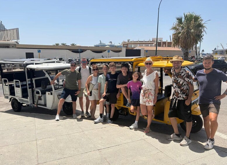 Un grupo de personas posando frente a un vehículo amarillo y otro blanco con remolque. 3
