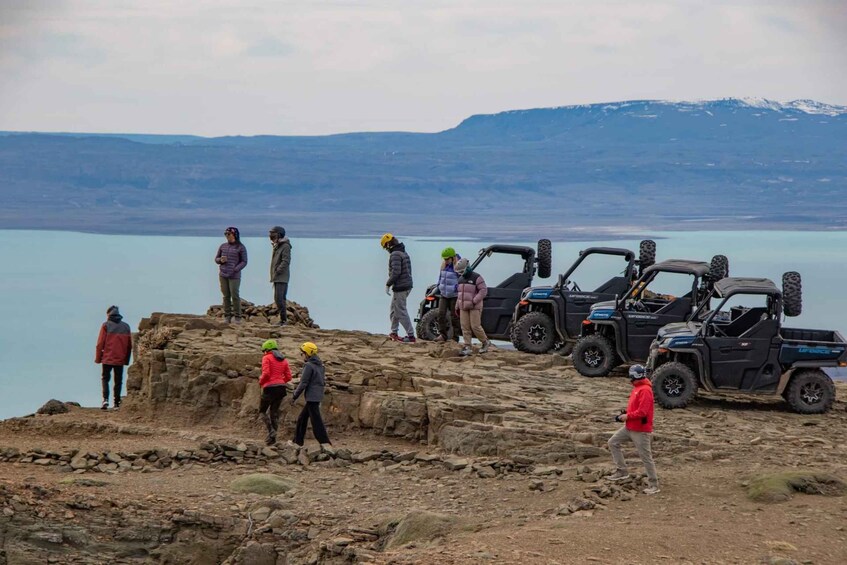 A group of people on a rocky outcrop with a lake and mountains in the background. 1