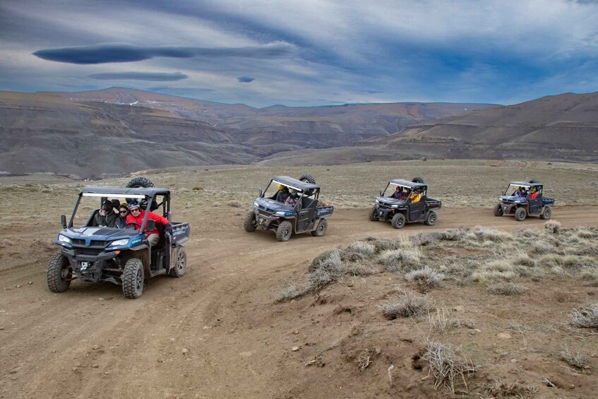 Four off-road vehicles on a dirt road in a desert landscape. 2