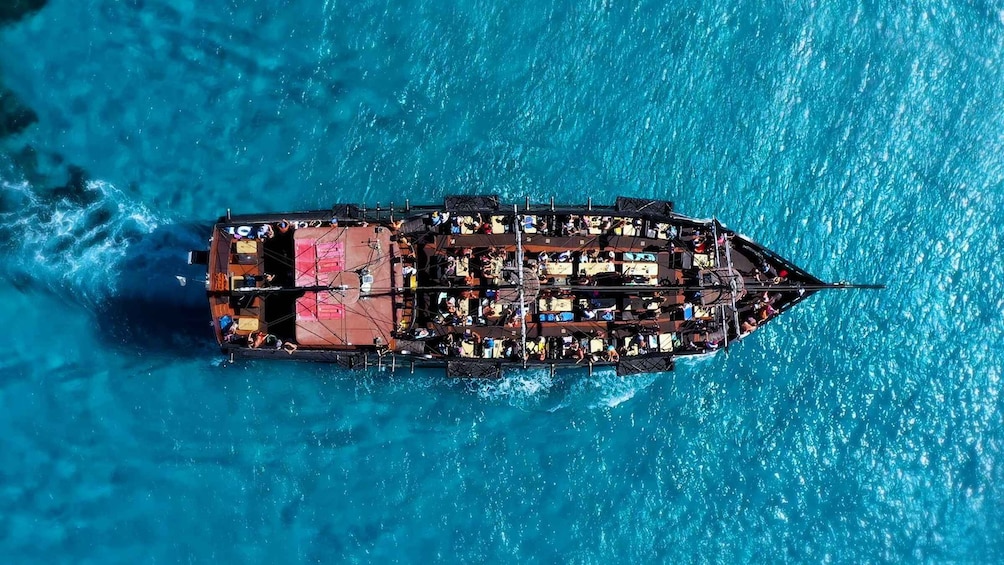 A large ship with multiple decks and a red superstructure, sailing on a deep blue ocean. 2